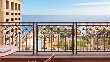 A balcony with a view of the sea and a building with columns.