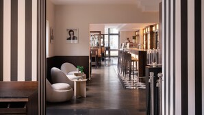 A modern interior with a bar area, seating, and a view into the kitchen. - Flemings Hotel München Schwabing (Munich)