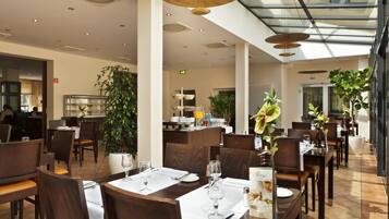 Un comedor moderno con mesas dispuestas para comensales, una zona de bar y una planta grande en maceta.