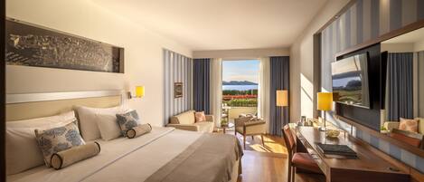 A hotel room with a large bed, a desk, a chair, a TV, and a view of the outdoors.