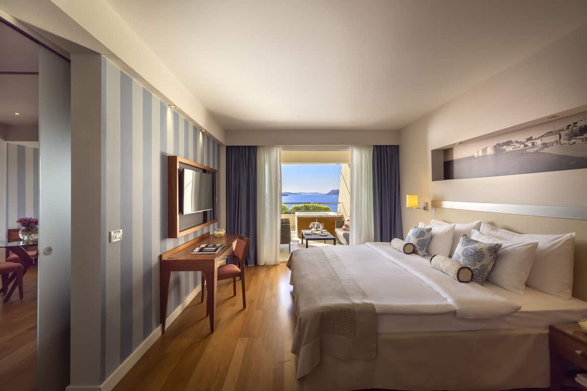 A hotel room with a large bed, a desk, and a view of the outdoors.