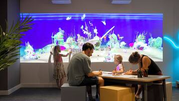 A room with a large aquarium, a table with people, and a plant.
