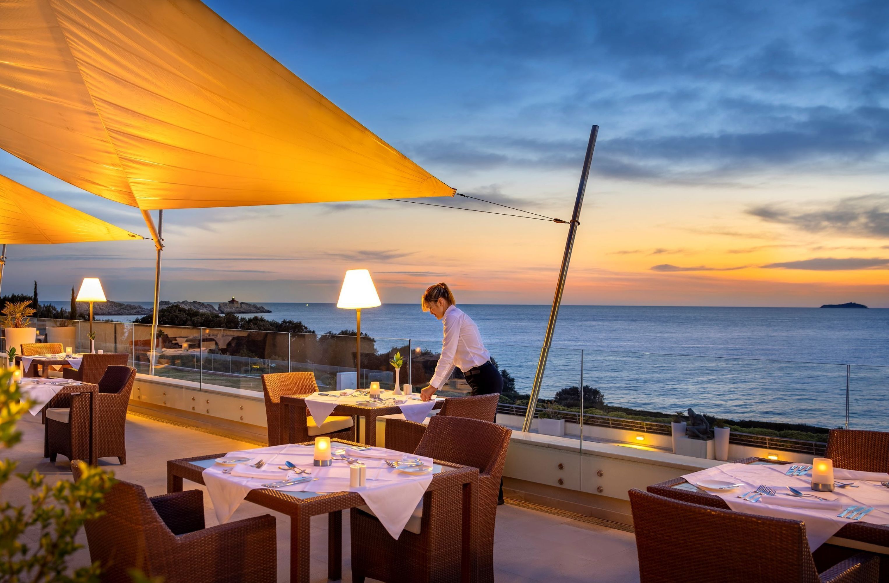 A restaurant with tables set for dining, overlooking the sea.