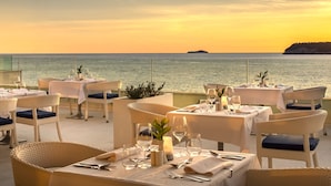 Un restaurante frente al mar, con mesas listas para recibir comensales y vistas al océano.