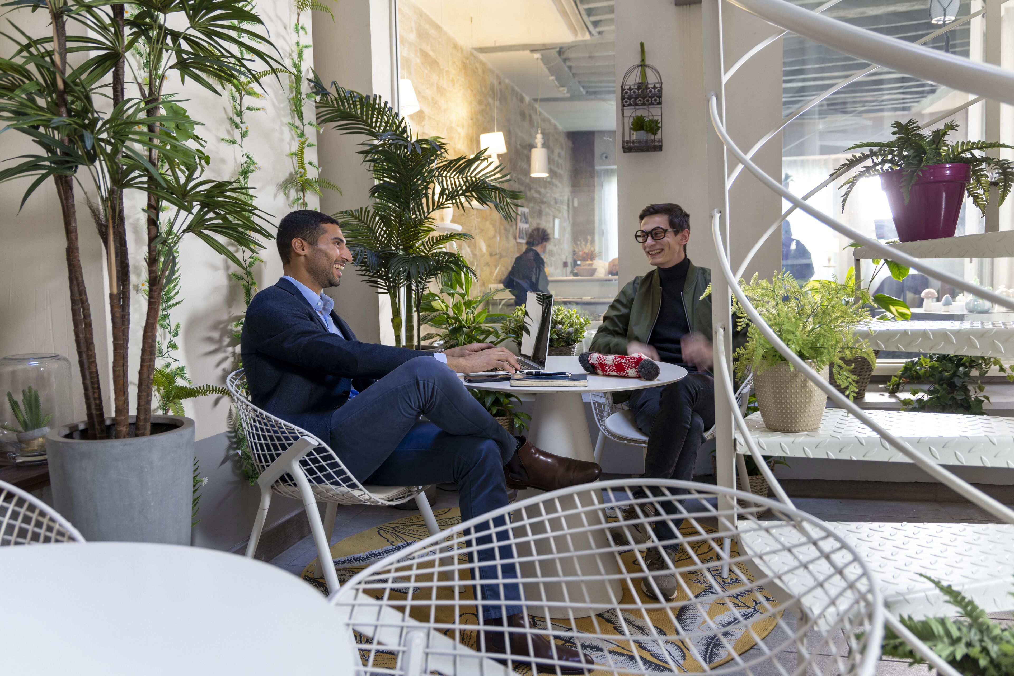 Un café doté d’une terrasse, de plantes en pot et d’un décor intérieur moderne.