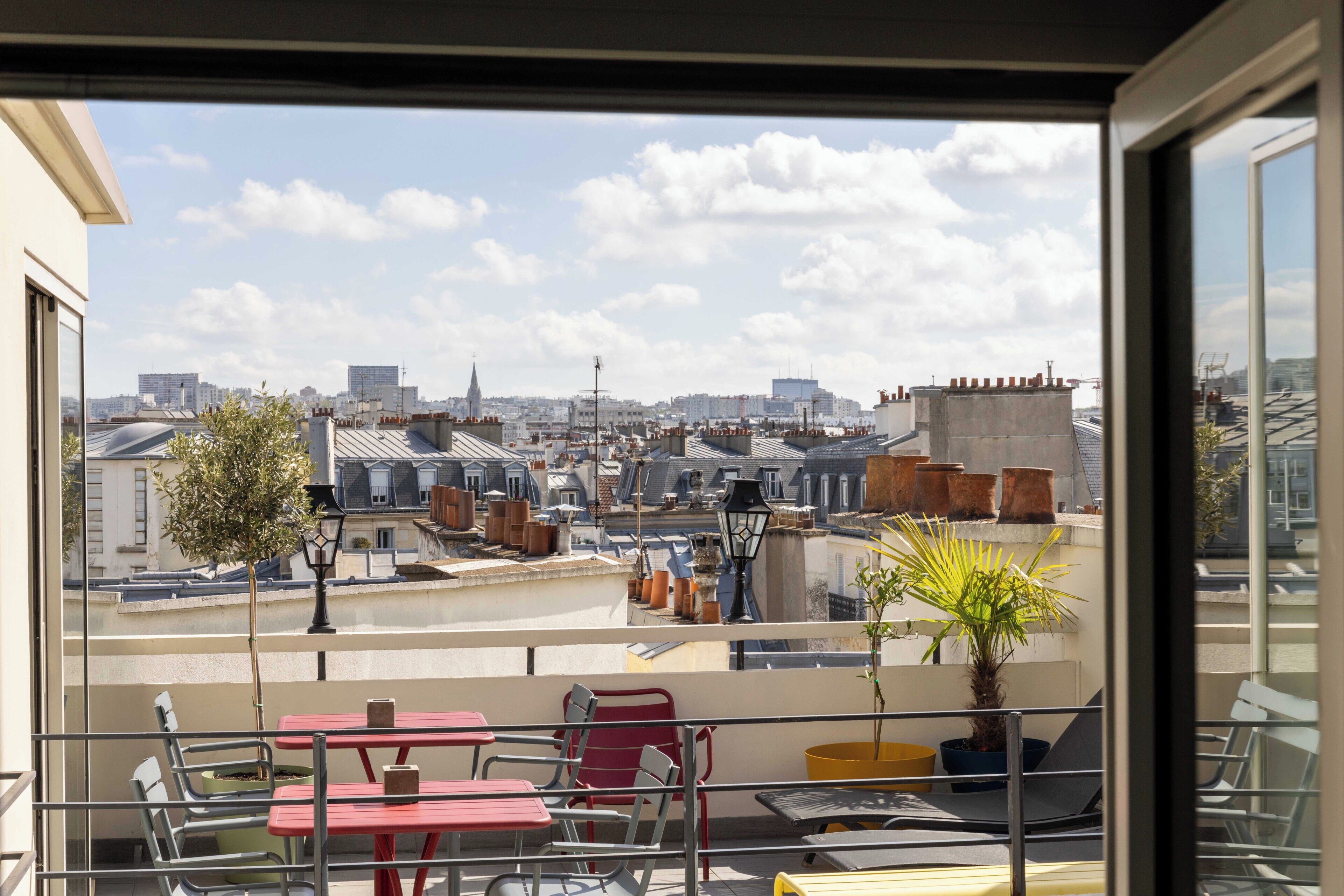 A balcony with a view of a cityscape, including buildings and a church steeple.
