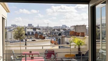 A balcony with a view of a cityscape, including buildings and a church steeple.