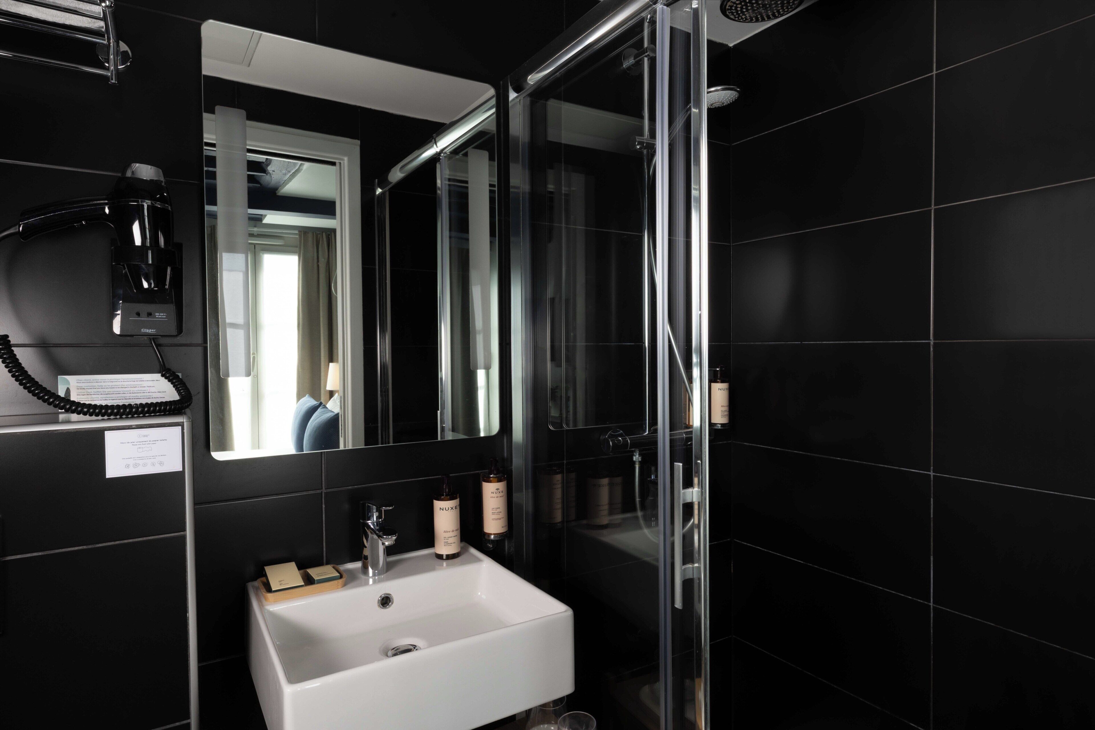 Une salle de bain moderne avec un lavabo blanc, un sèche-cheveux et un miroir.