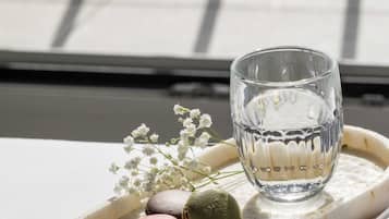 A tray with macarons and a glass of water on a table near a window.