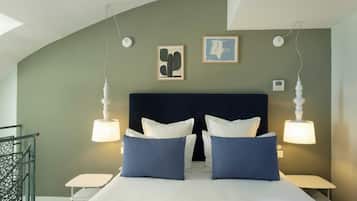 A bedroom with a curved ceiling, a dark headboard, two bedside tables, a bed with white and blue bedding, and two wall-mounted lamps.