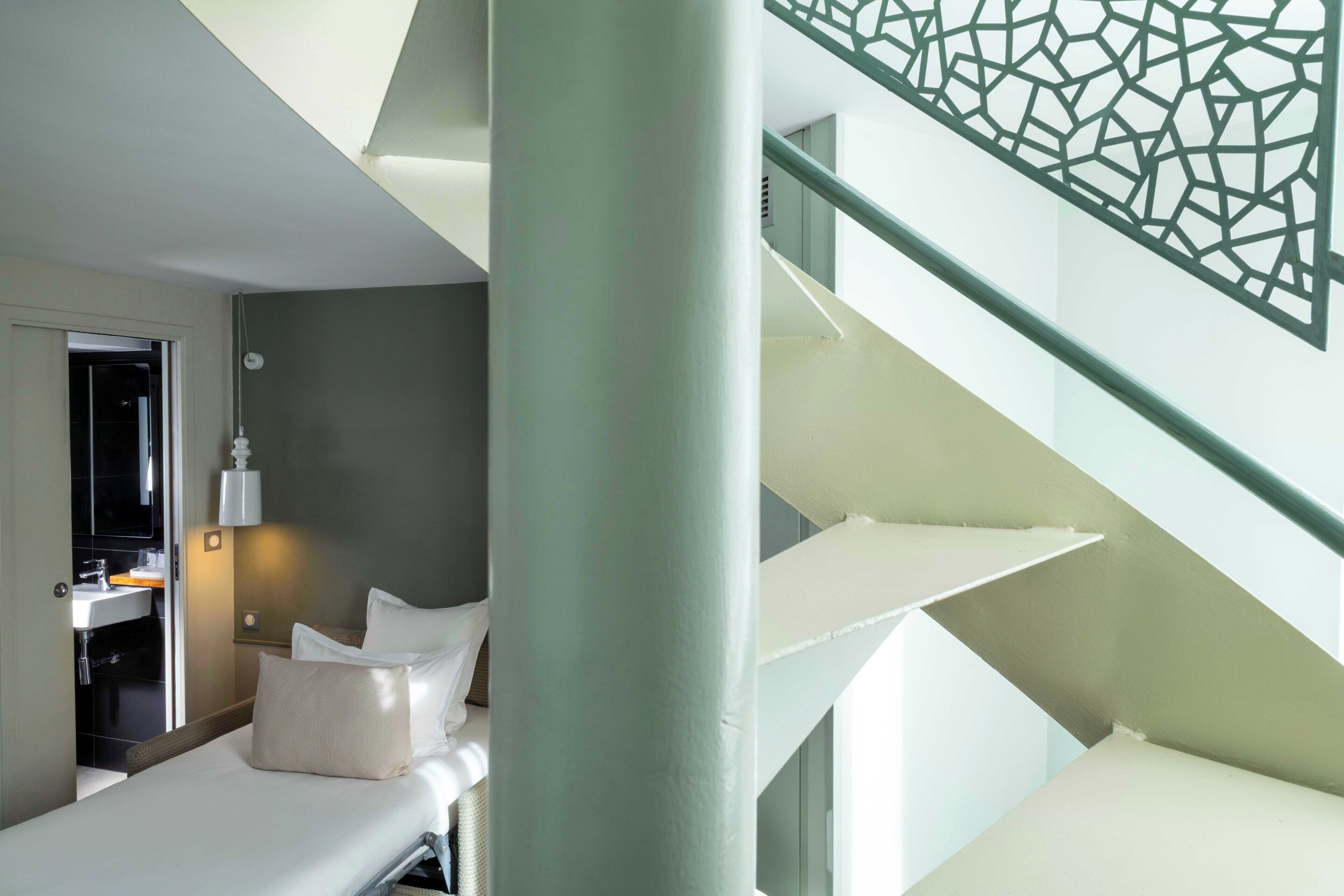 Une chambre d’hôtel moderne équipée d’un lit, d’une salle de bain et d’un escalier.