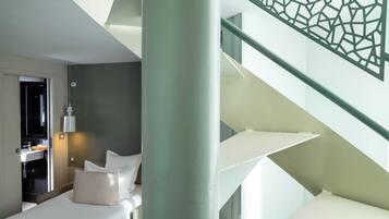 Une chambre d’hôtel moderne équipée d’un lit, d’une salle de bain et d’un escalier.