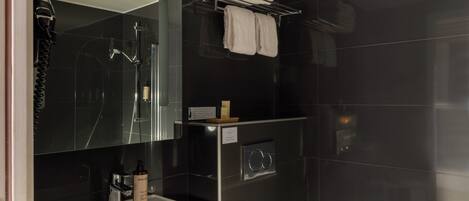 A modern bathroom with a glass shower enclosure, a sink with a mirror, and a towel rack with folded towels.