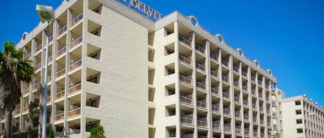A multi-story hotel with a prominent "HOTEL BELVEDERE" sign, balconies on each floor, and a clear blue sky in the background.