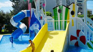Parque acuático con un tobogán amarillo, uno azul y blanco, y una zona de piscina.