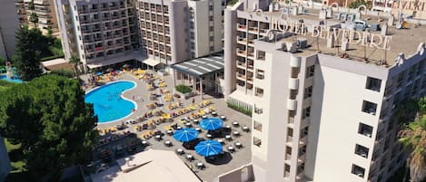 A hotel complex with multiple buildings, a swimming pool, outdoor seating areas, and a rooftop terrace.