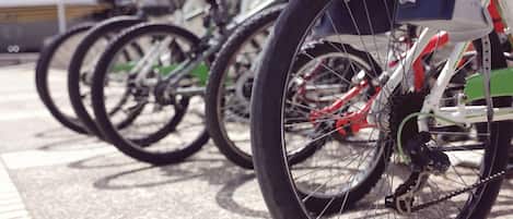 A row of bicycles parked in an outdoor area with a tiled floor.