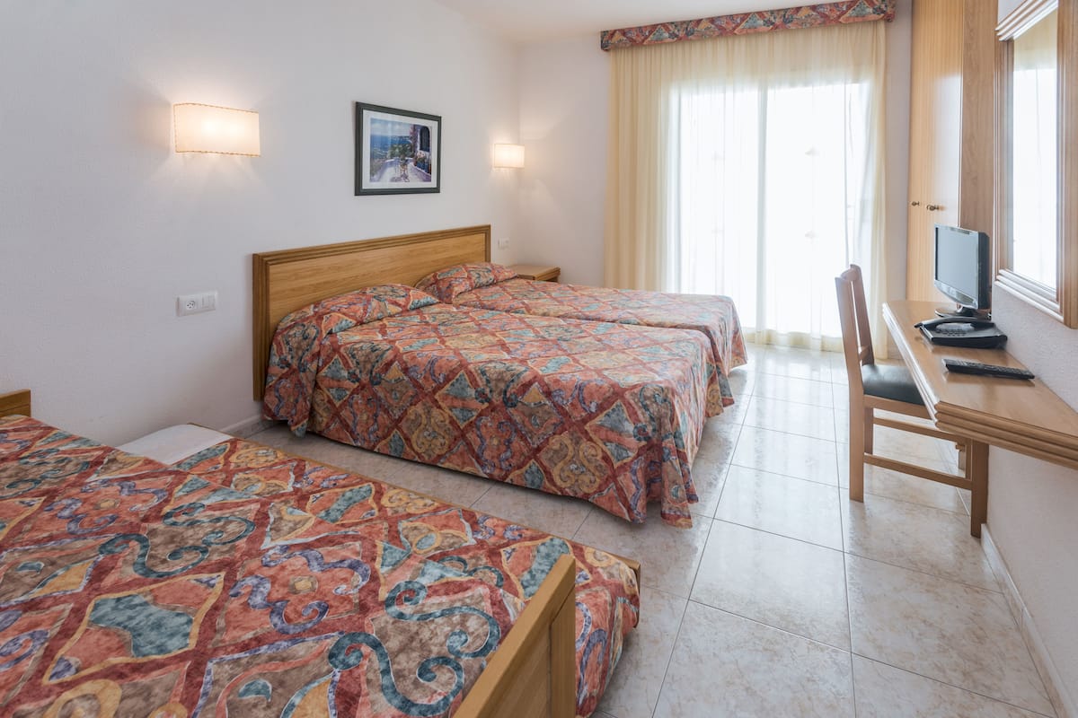 Una habitación de hotel con dos camas, un escritorio con una computadora y una silla.
