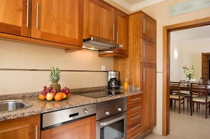 Una cocina con gabinetes de madera, encimera de granito, electrodomésticos de acero inoxidable y un área de comedor visible a través de un umbral abierto.