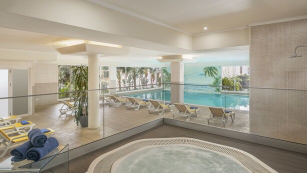 A modern indoor pool area with lounge chairs, a hot tub, and a view of the ocean. - Dorisol Buganvilia Studio Hotel (Funchal)
