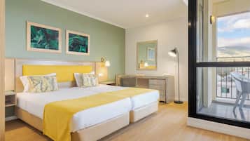 Une chambre d’hôtel avec un lit double, un bureau, une chaise et une grande fenêtre donnant sur la ville.