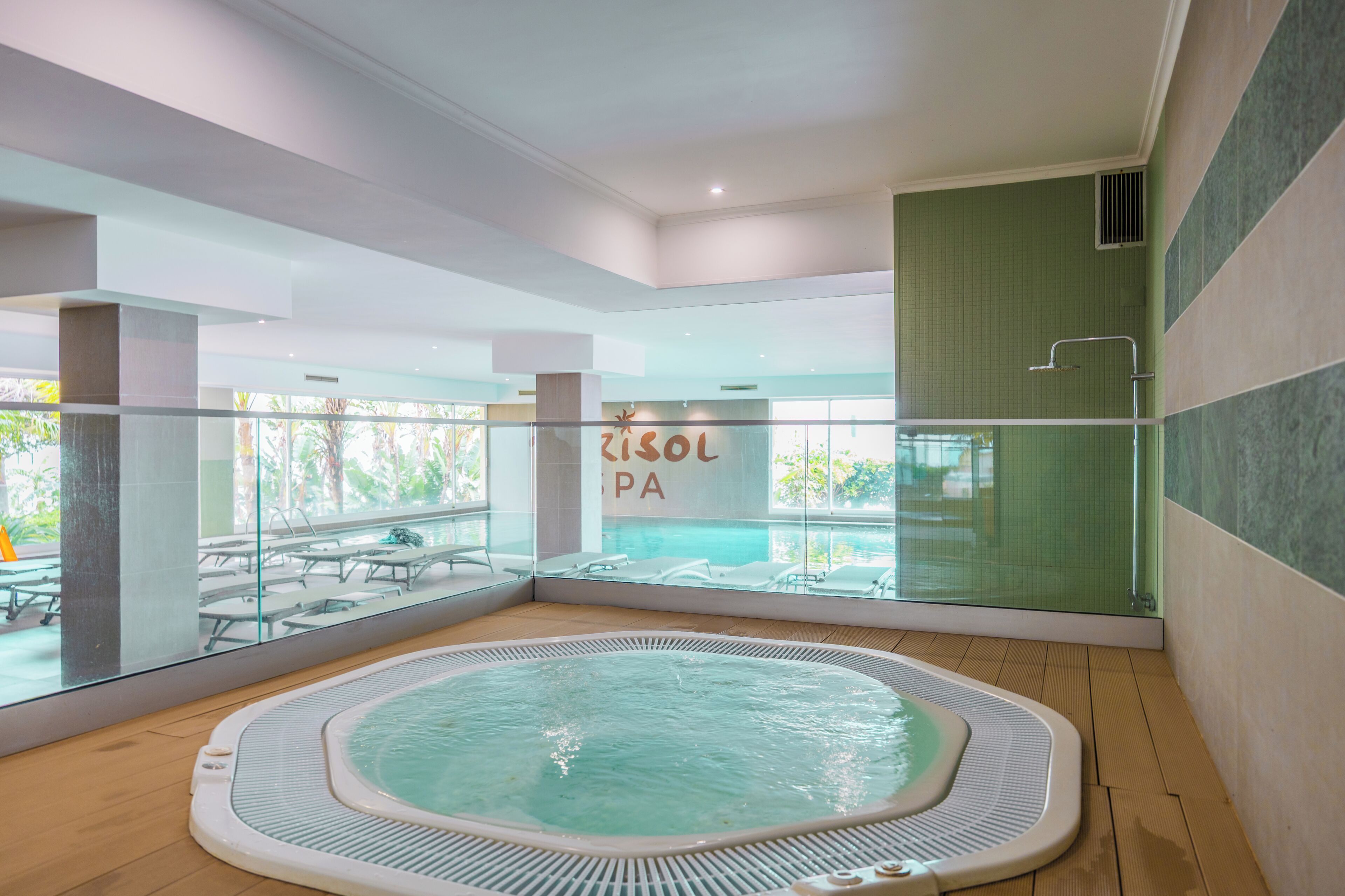 Un'area benessere con vasca idromassaggio, poltrone relax e vista piscina.