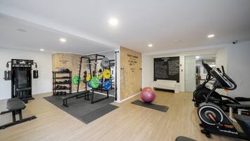 A modern gym with weightlifting equipment, cardio machines, and a motivational quote on the wall.