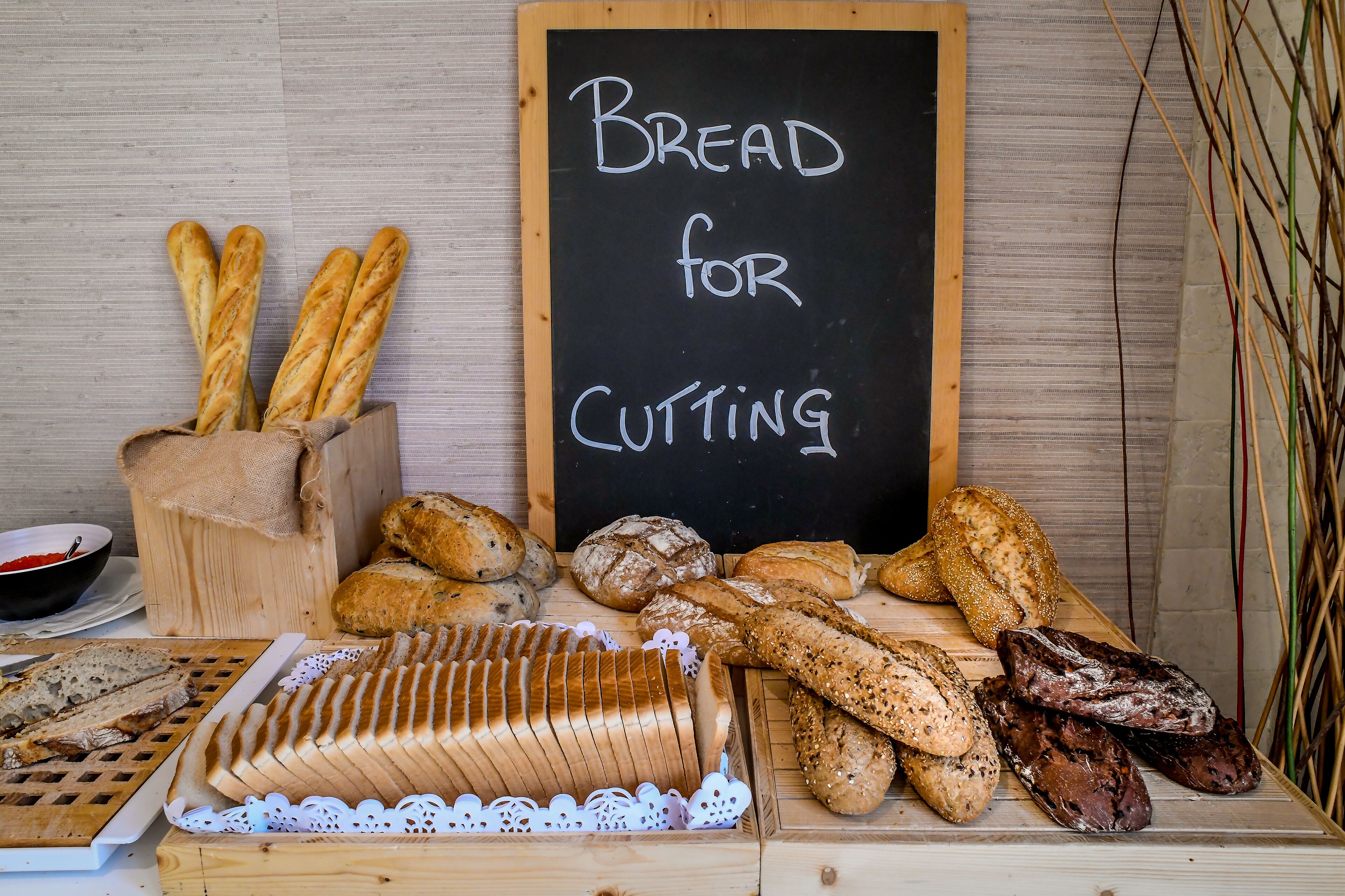 Variedad de panes expuestos sobre una tabla de madera con un letrero que dice 'Bread for Cutting'.