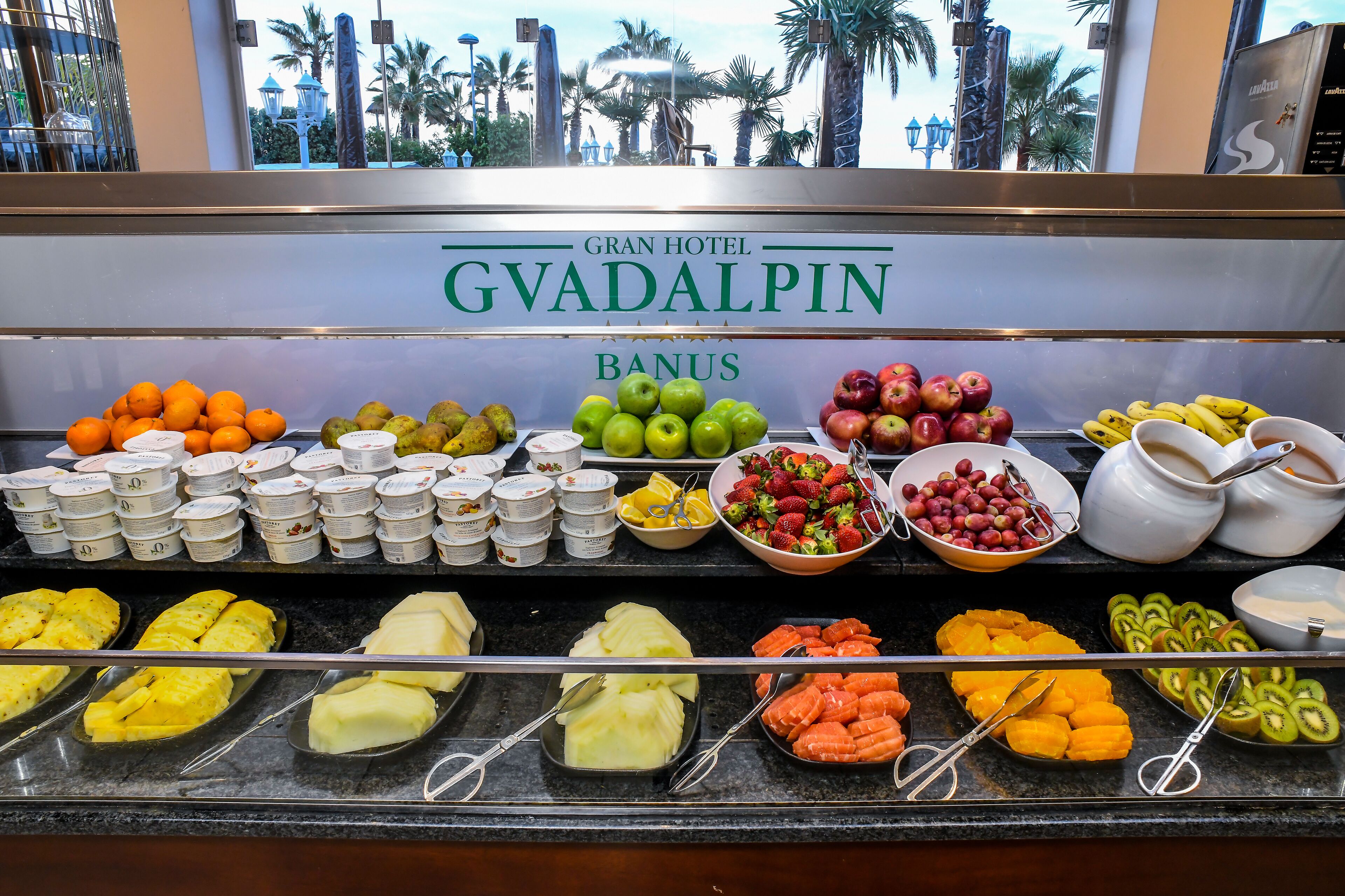 Een buffet met diverse soorten fruit, yoghurt en boter in het Gran Hotel GVADALPIN.