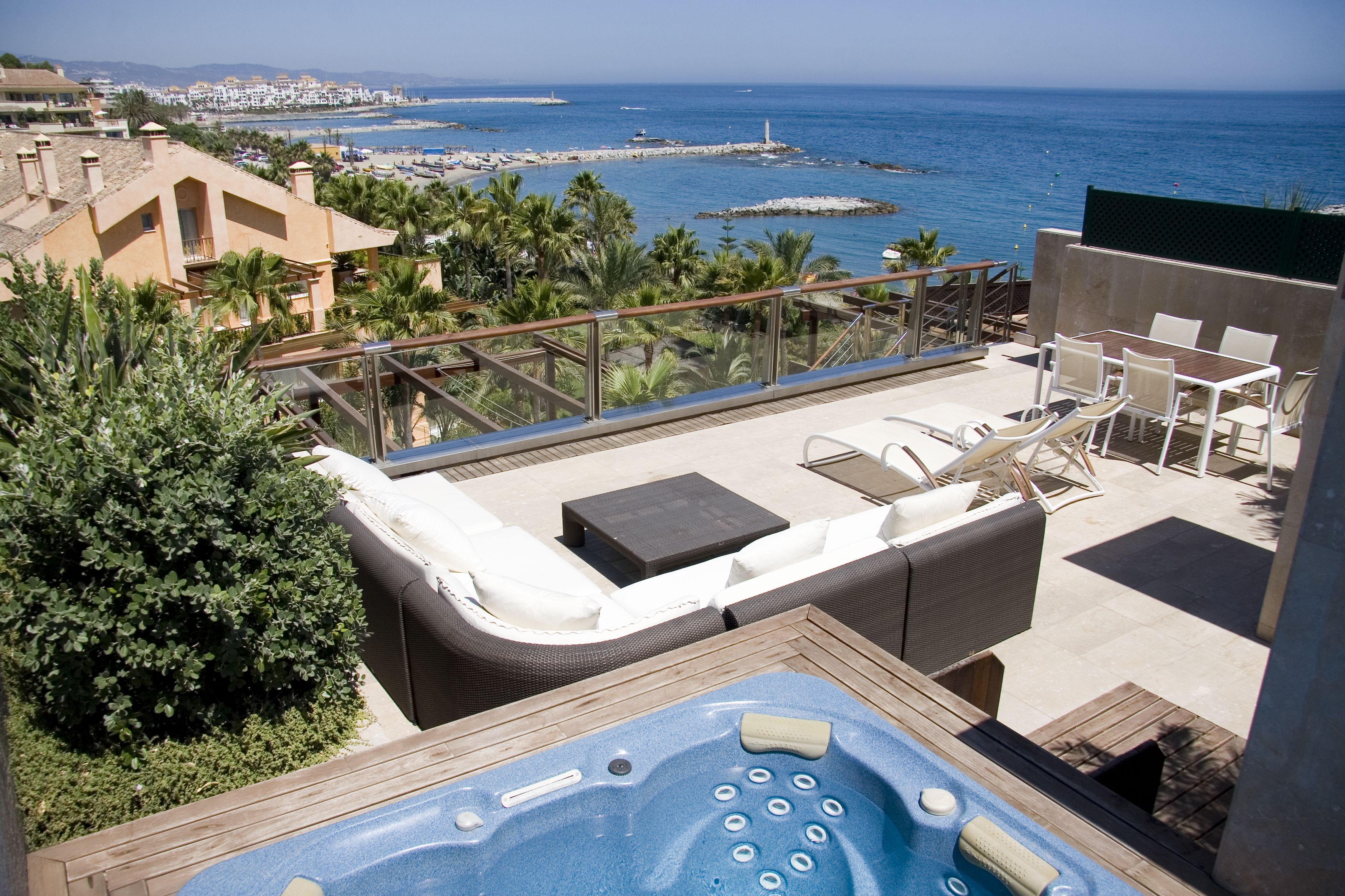 Eine Dachterrasse mit Whirlpool, Liegestühlen und Blick auf das Meer.