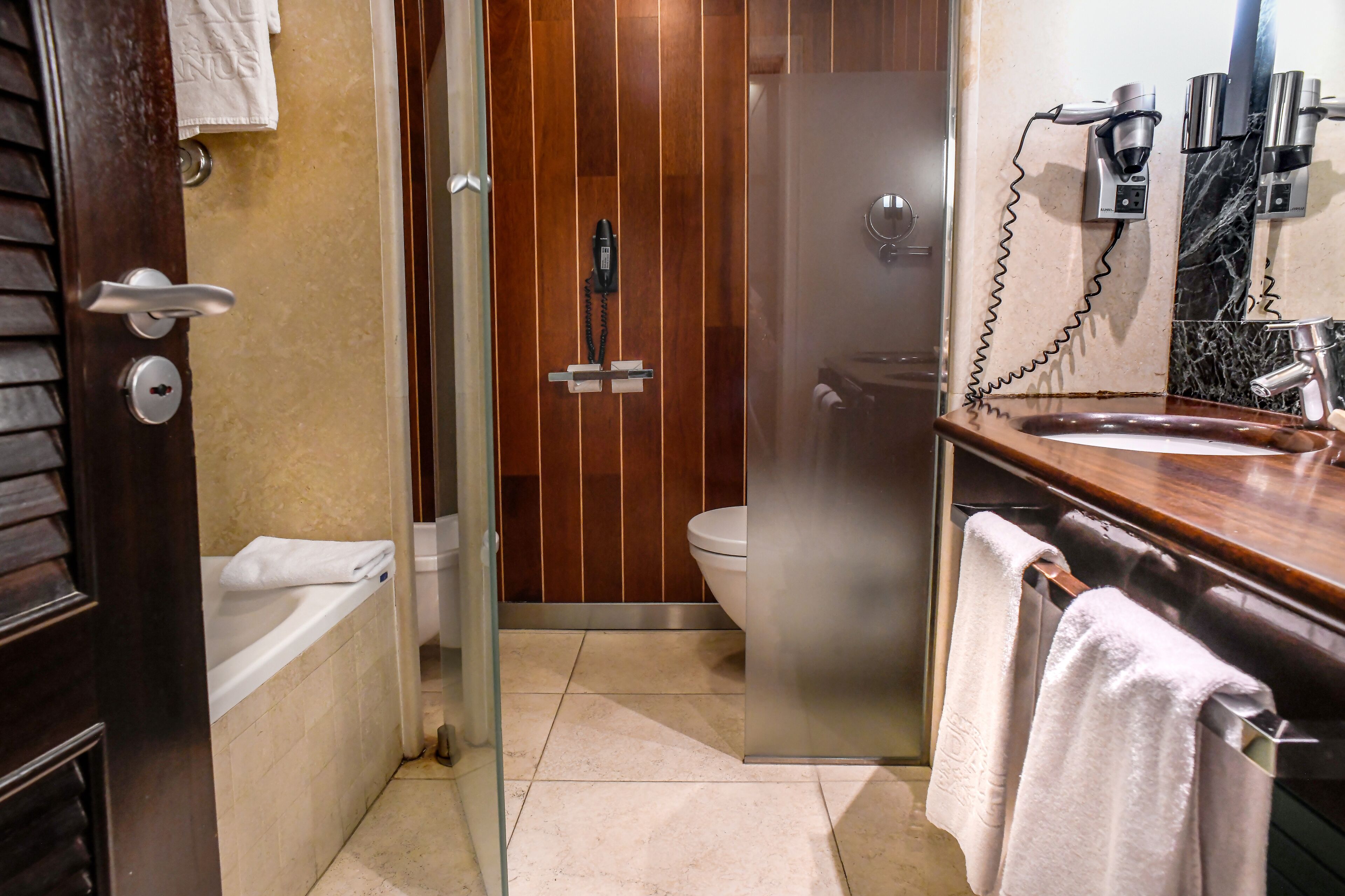 Une salle de bain avec une douche à parois de verre, des toilettes et un lavabo, avec une serviette posée sur le comptoir.