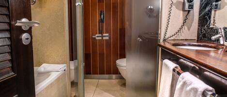 Un baño con cabina de ducha de vidrio, inodoro y lavabo con una toalla colgada en el mostrador.