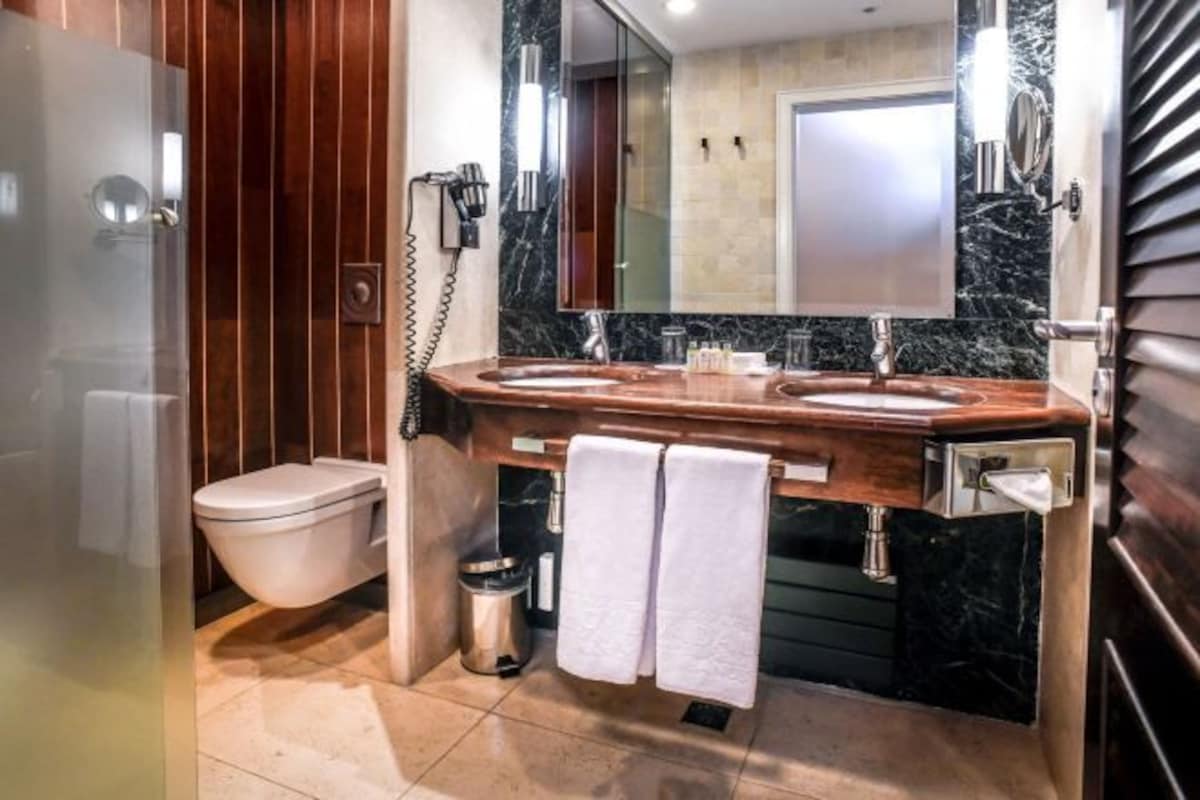 A modern bathroom with a wooden vanity, a toilet, and a shower area.