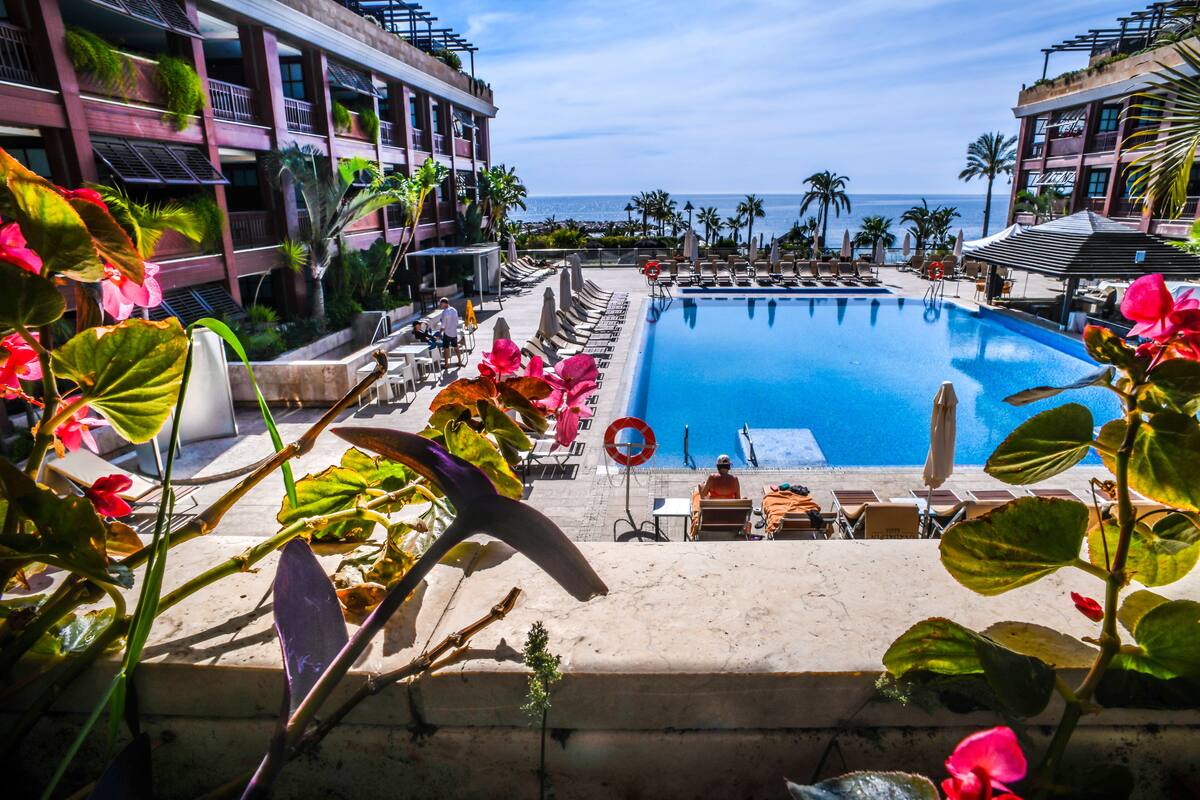 A hotel pool area with lounge chairs and umbrellas, overlooking the ocean.
