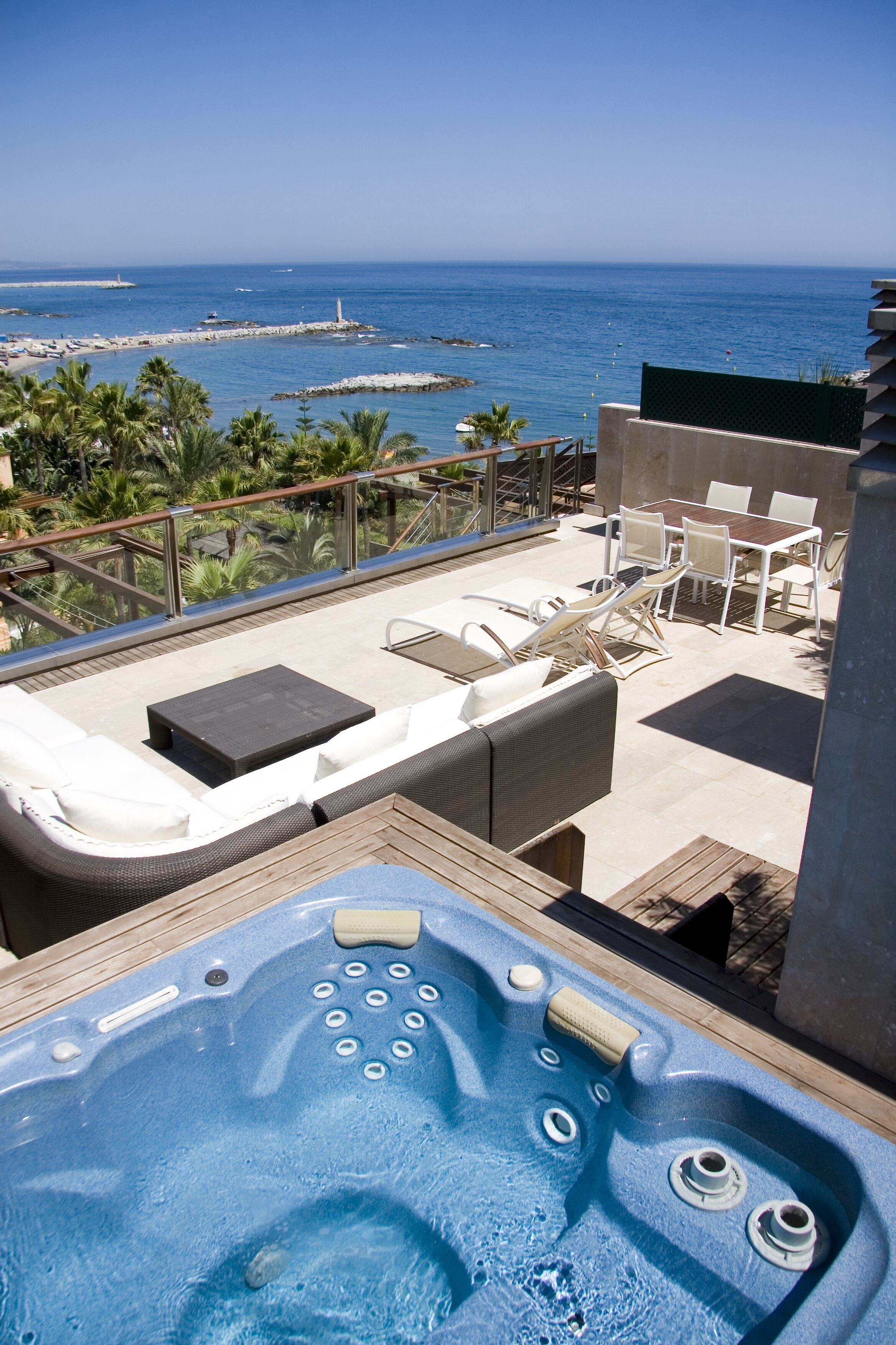 Une terrasse sur le toit avec un jacuzzi, des chaises longues et une vue sur l’océan.