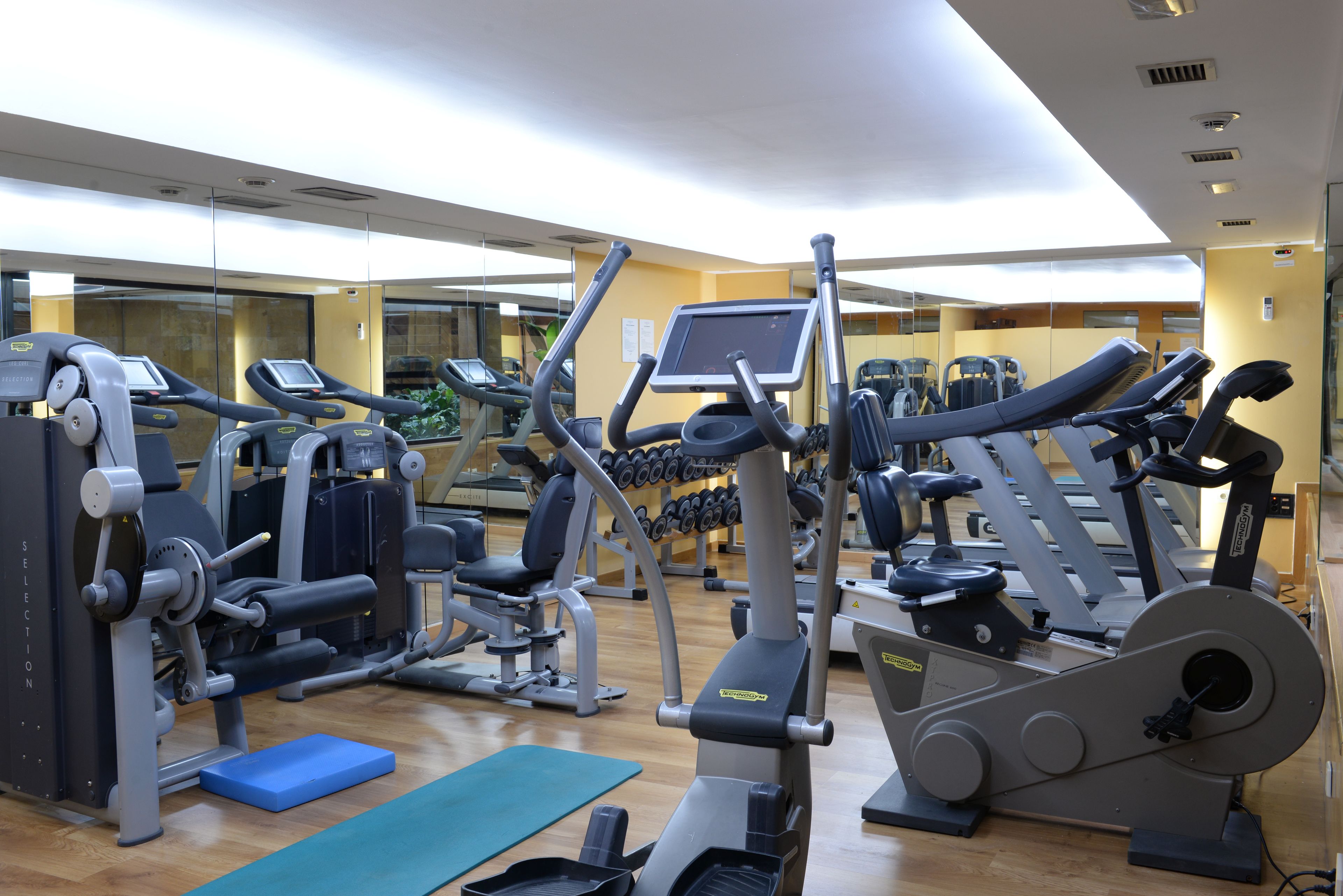 A gym with cardio machines, weight machines, and a mirror wall.