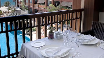 Mesa posta para refeição, com vista para o oceano e um hotel ao fundo.