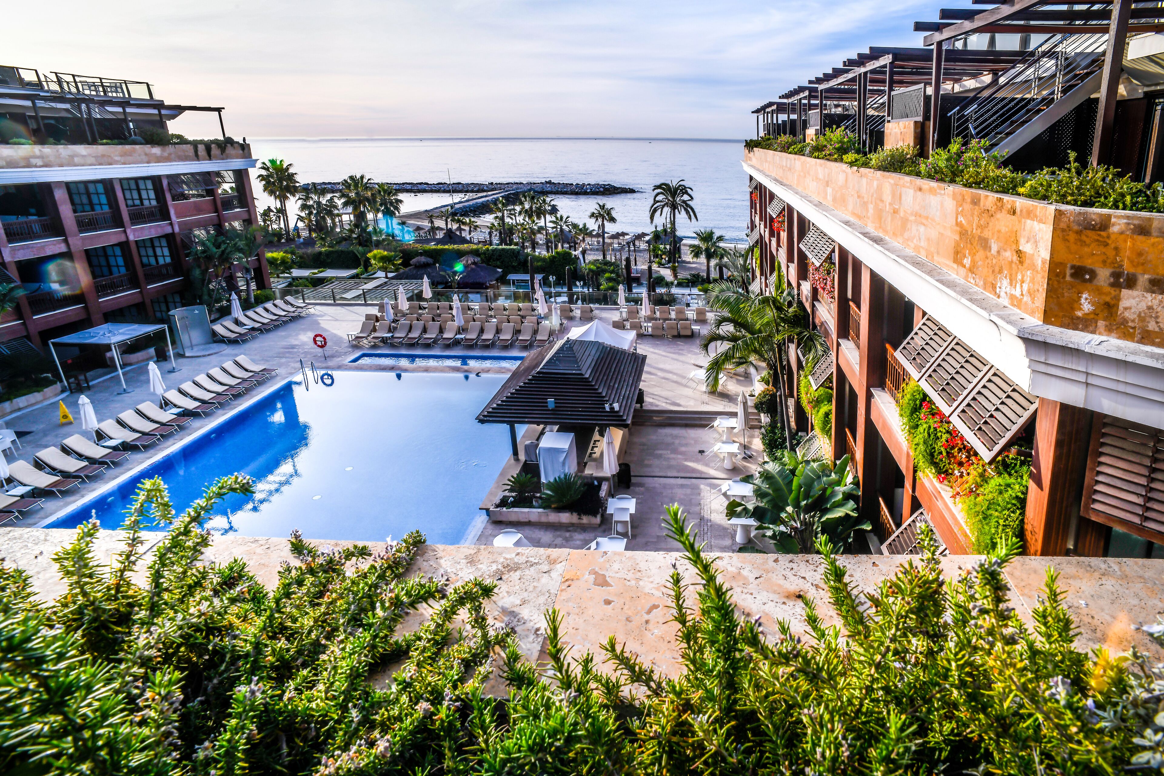 A rooftop pool with lounge chairs and a view of the sea.