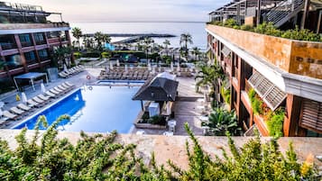 A rooftop pool with lounge chairs and a view of the sea.