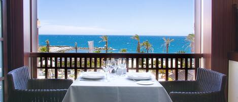 A dining table set for two with a view of the ocean.