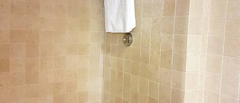 Ein Badezimmer mit einer Badewanne, einem Handtuchhalter mit zwei Handtüchern und beige gefliesten Wänden.