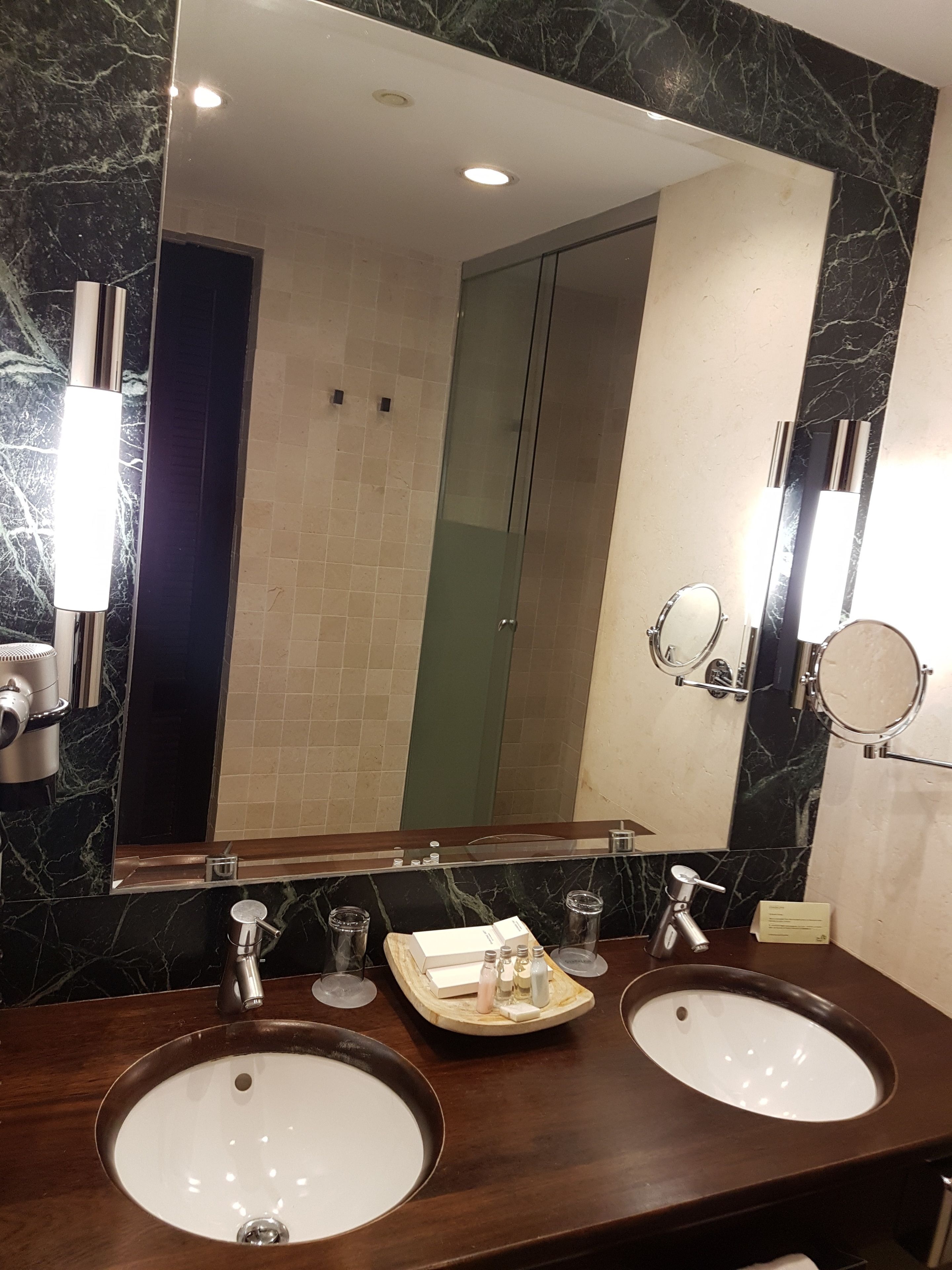 Un baño con dos lavamanos, un espejo grande y un perchero para toallas.