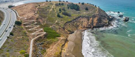 A coastal road with a winding path leading to a beach.
