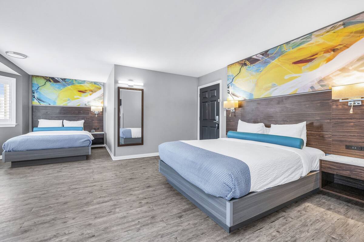 A modern hotel room with a large bed, a smaller bed, and a seating area.