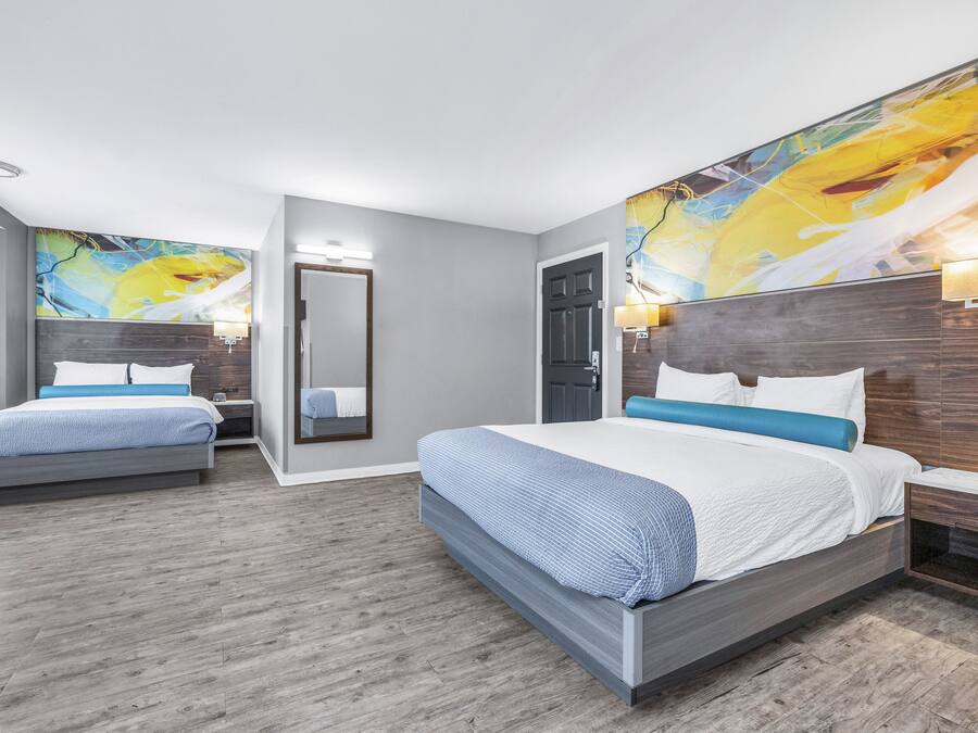 Quarto de hotel moderno com uma cama grande, uma cama menor e uma área de estar.