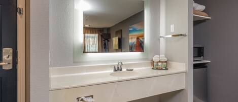 A modern bathroom with a large mirror, a sink, and a towel dispenser.