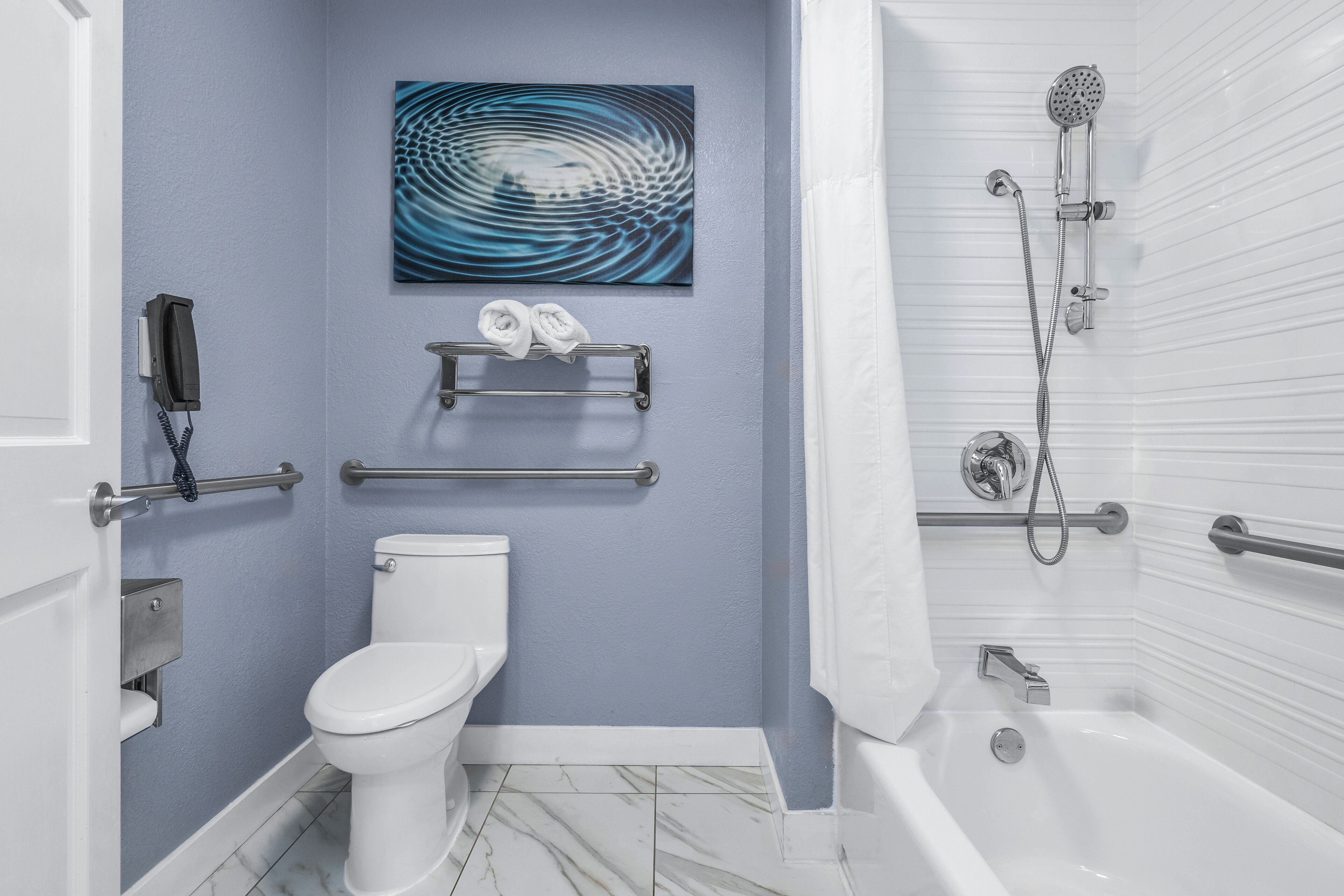 A bathroom with a toilet, a shower, a towel rack, and a phone.
