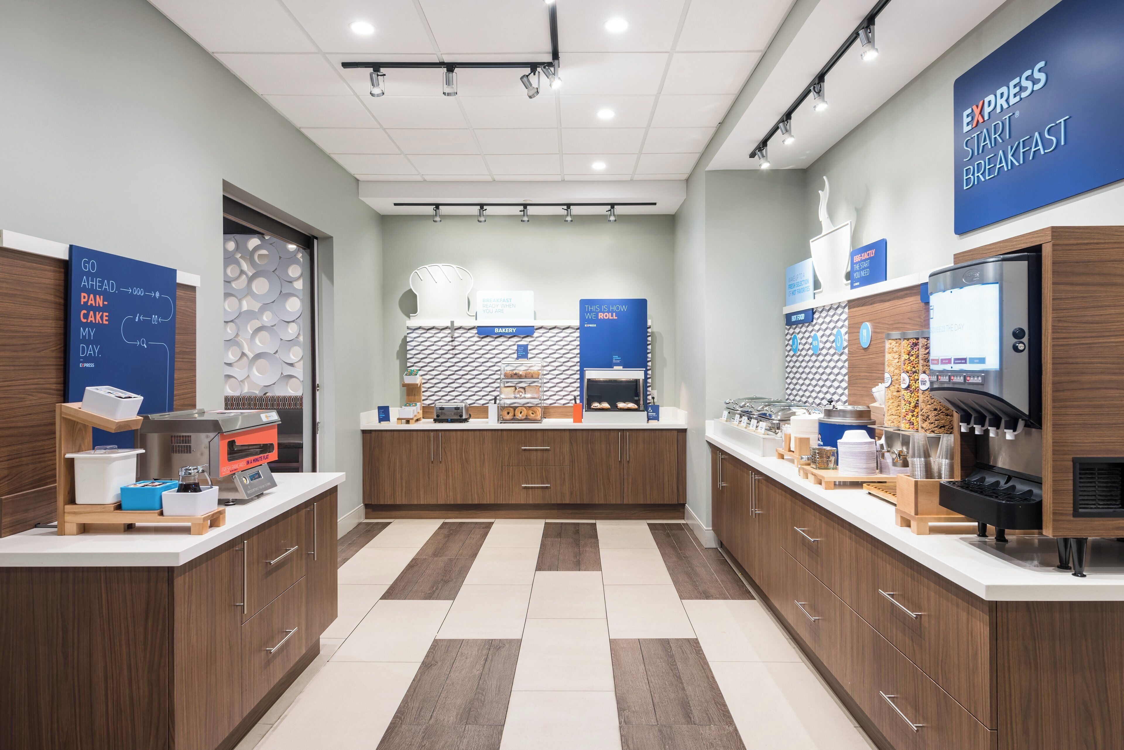 A modern breakfast area with a bakery counter, a coffee station, and a self-serve beverage dispenser.