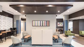 A modern interior with a central seating area, a wall-mounted artwork, and a mix of seating options.