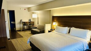A hotel room with a large bed, a desk with two chairs, a lamp, and a nightstand. - Holiday Inn Express & Suites Milton by IHG (Milton)